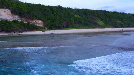 Tourists-Walking-And-Standing-By-The-Shore-Of-Gunung-Payung-Beach-During-Daytime-In-Bali,-Indonesia