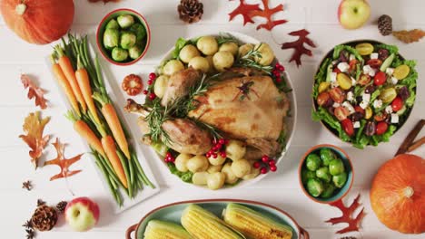 video de bandeja con pavo asado, platos diversos y decoración de otoño en superficie blanca