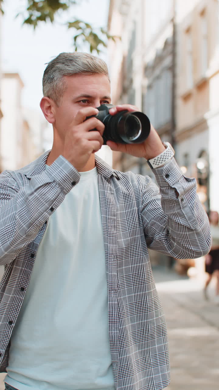 hombre caucásico maduro feliz tomando fotos en la cámara mirando a su alrededor mientras camina por la ciudad