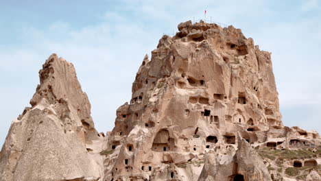 vista del castillo de uchisar con bandera turca en la montaña en capadocia