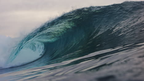 low ocean surface view of green crystal clear wave barreling in slow motion