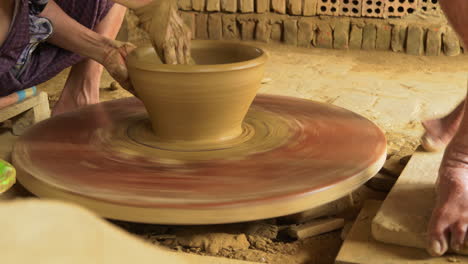 close-up footage of a skilled potter in vietnam turning clay into traditional pottery on a foot-turning table at a fast pace, showcasing the artistry and craftsmanship of handmade pottery