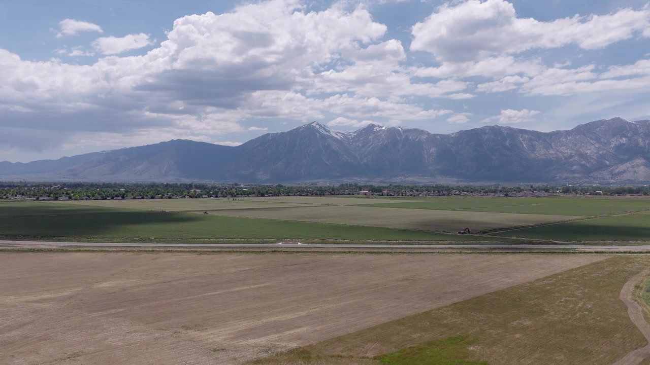 Stigende droneoptagelse af landbrugsmarkerne og dalbunden nær Minden, Nevada, der viser det smukke landskab med de majestætiske Sierra Nevada-bjerge, der rejser sig i det fjerne.