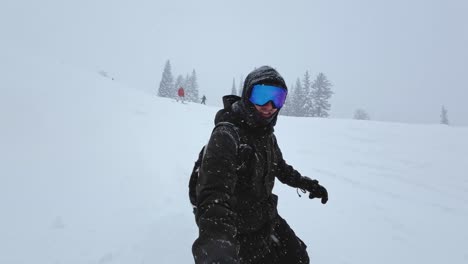 handheld point of view shot of a white man in his twenties dressed in snow gear snowboarding down a steep hill at a snowy ski resort during a cold snowstorm in the rocky mountains of utah