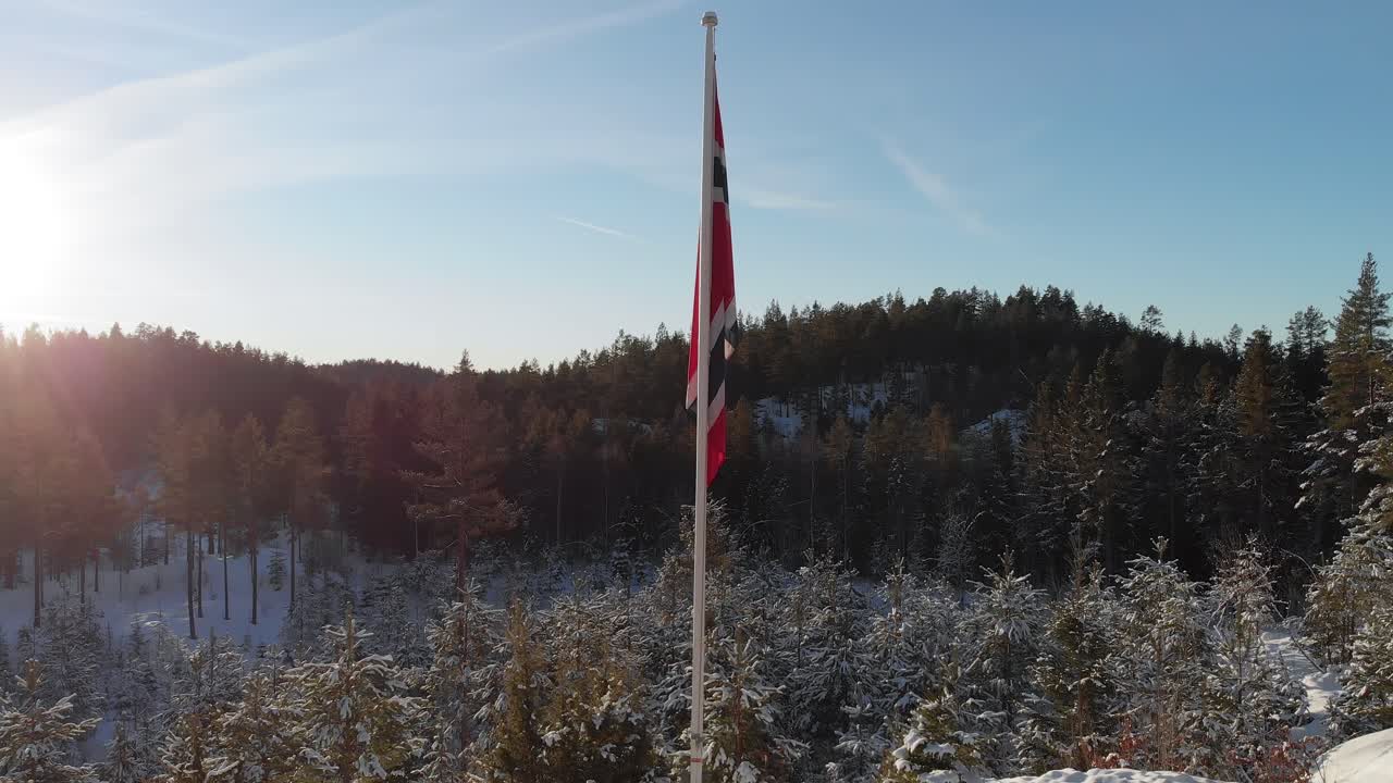 Flaga norweska na maszcie stojąca na zaśnieżonej górze zimą w Norwegii.