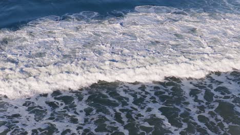surfers ride powerful waves under clear skies at gold coast, australia. dynamic ocean scene with vibrant blue and white contrasts