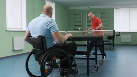 a man in a wheelchair plays ping pong. people with disabilities play table tennis. rehabilitation of the disabled. sport.