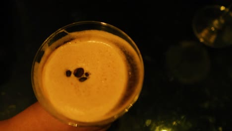 hand holding espresso martini in dim lighting