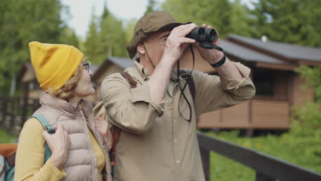 una pareja de ancianos explorando la naturaleza con binoculares.