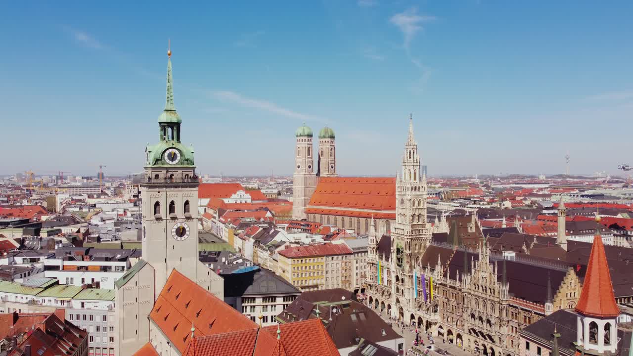 Aerial establishing of Munich Marienplatz with Frauenkirche, St Peters Church and Old Town Hall, bustling city below during daytime, Germany