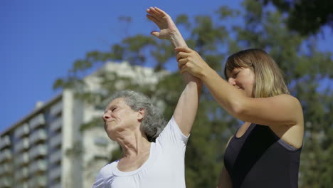una anciana sonriente estirando los brazos antes del entrenamiento.