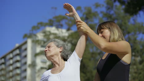 smiling elderly lady stretching arms before training.