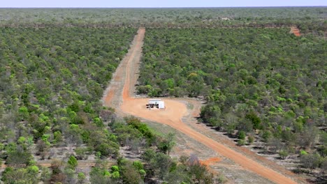 Drone-shot-of-a-dirt-road-on-a-farm-in-outback-Australia-with-a-huge-diesel-water-bore