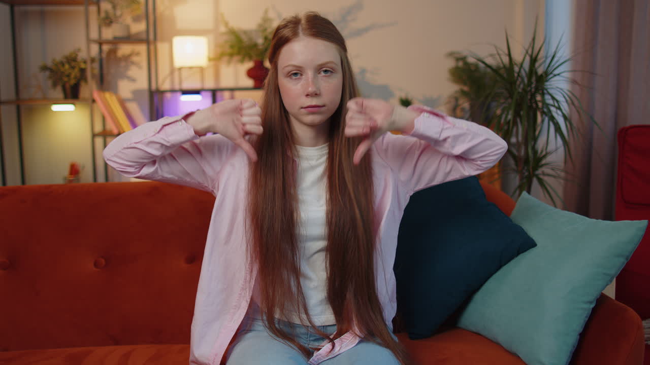 расстроенная девочка показывает большой палец вниз, не нравится плохая работа, неодобрение, неудовлетворенная обратная связь дома