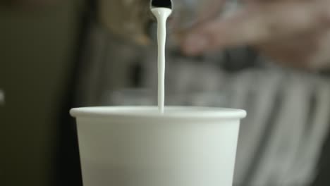 a barista pours milk into a coffee cup