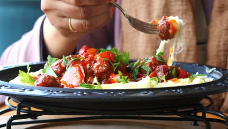 woman eating delicious meatballs with mashed potatoes and red sauce