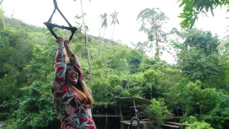 woman jumping into water with a swing rope