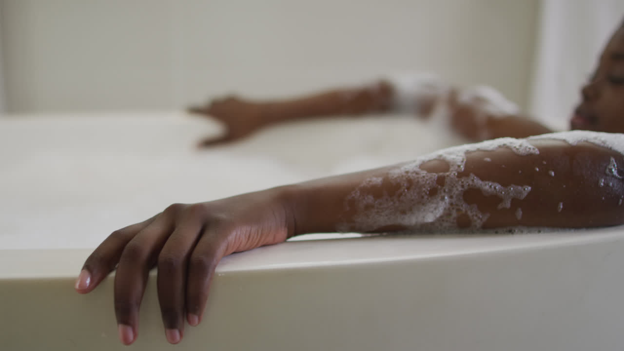 African american attractive woman relaxing in foam bath in bathroom