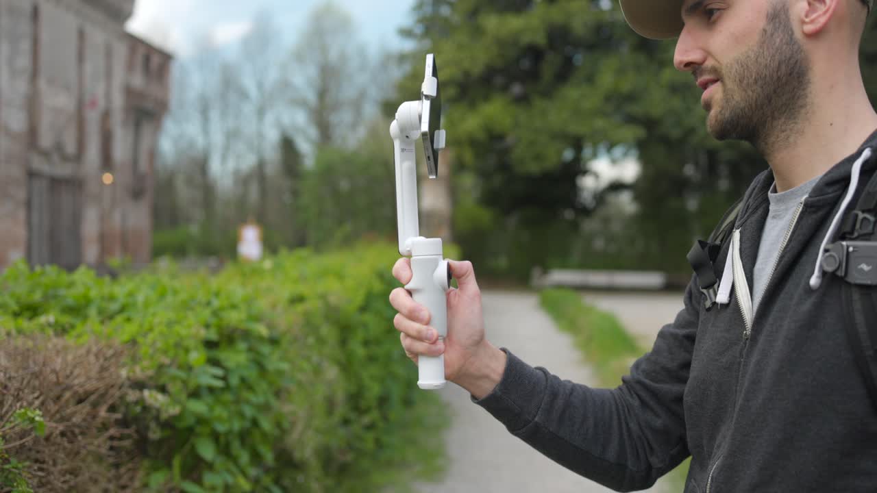 joven hombre adulto moderno grabando video con un nuevo teléfono inteligente gimbal insta360 flujo al aire libre
