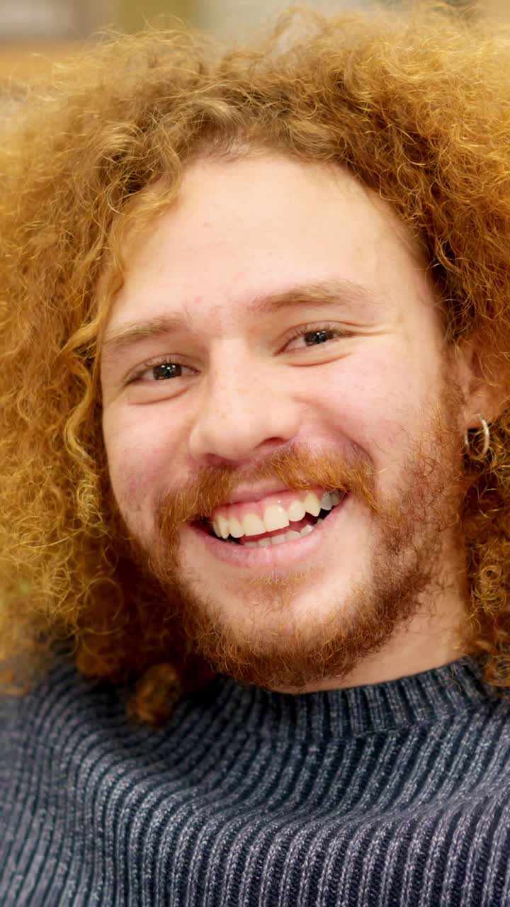 Man with curly hair smiling at camera in a coworking