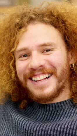 man with curly hair smiling at camera in a coworking