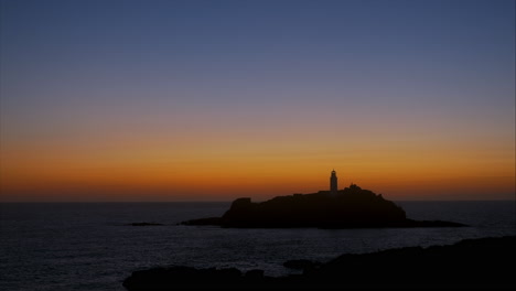 Puesta-De-Sol-Dorada-Y-Cálida-En-El-Faro-De-Godrevy-Con-Colores-Naranja,-Ocre-Y-Azul,-Tiro-Panorámico