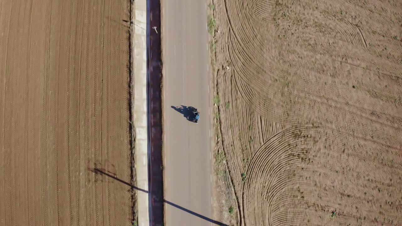 vista aérea de arriba hacia abajo del motociclista en una carretera rural vacía, disparo de drones de gran ángulo