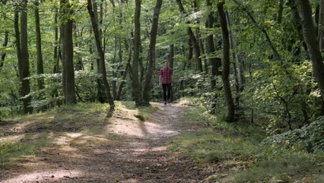 Portrait-of-young-Caucasian-man-hiking-in-forest-enjoying-sunny-summer-day