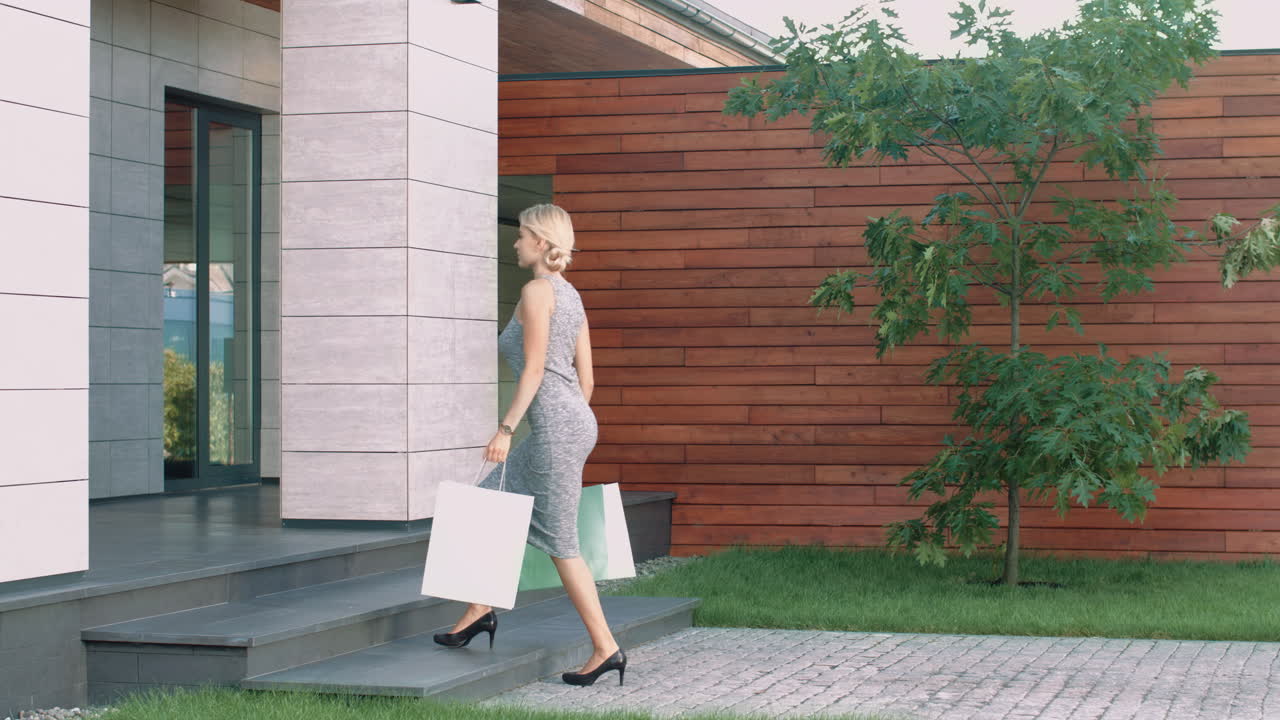 쇼핑 가방 을 들고 고급 아파트 에 들어가는 여자. 집 으로 돌아오는 여자 고객