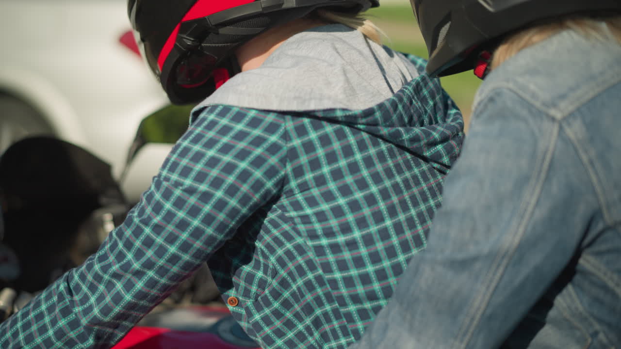 전력 자전거를 타고 있는 두 여성의 클로즈업 뷰. 뒤에 있는 여성은 색 자동차의 흐릿함과 근처에 보이는 배경 풍경과 함께 교통에서 기다리는 동안 라이더를 단단히 붙잡고 있습니다.