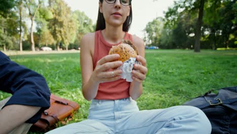 woman eating a hamburger in a park