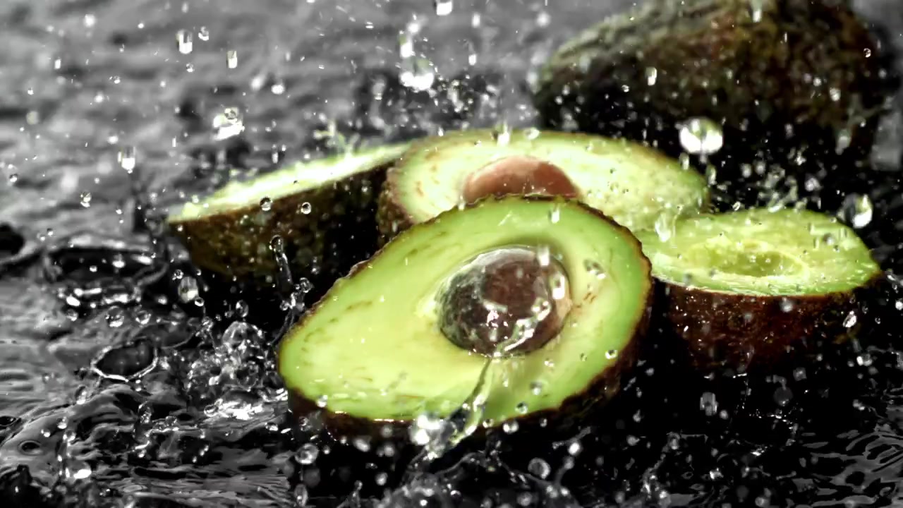 Acqua che schizza su avocado verdi freschi al rallentatore