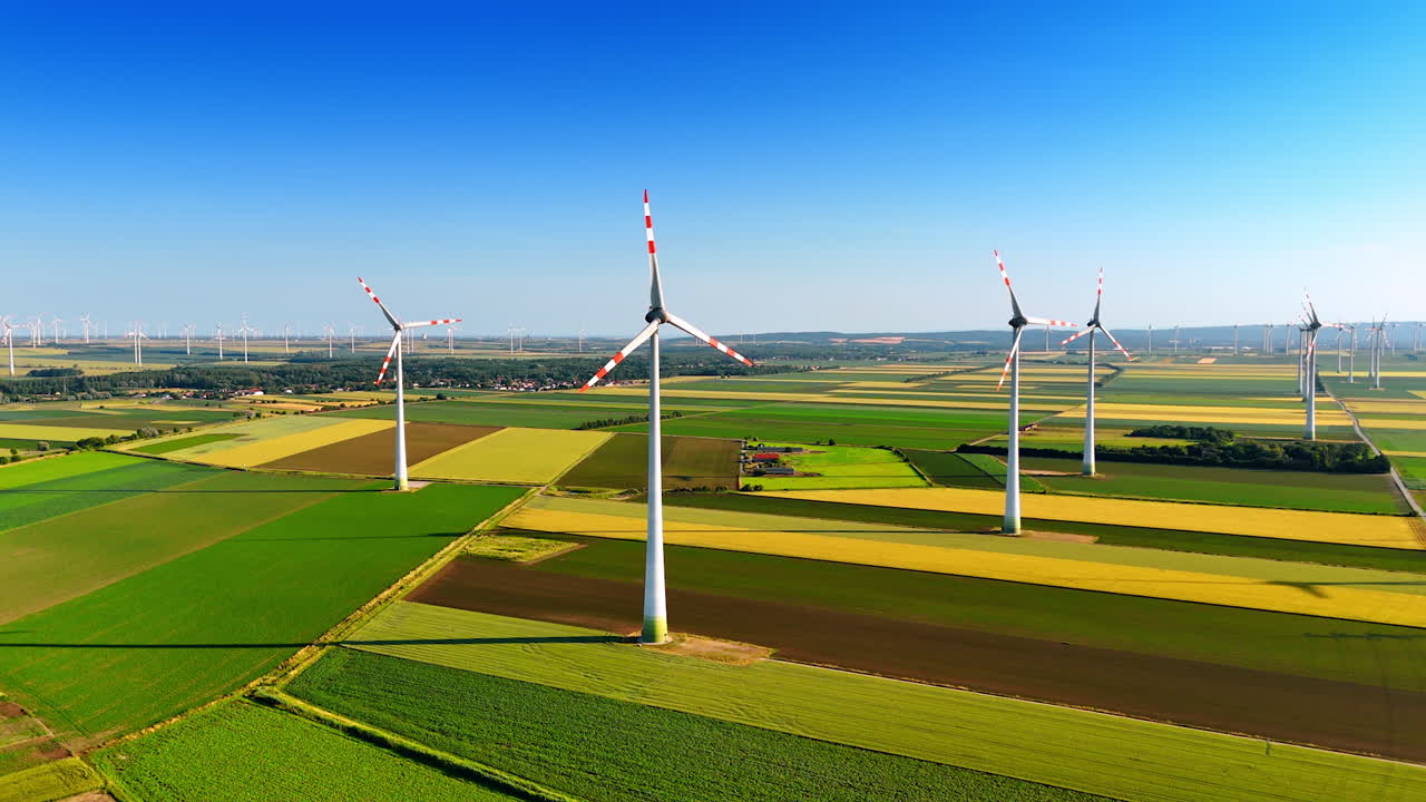 Wind turbines rise in Europe. Wind turbines dominate a vast green field under a clear blue sky, highlighting renewable energy in Europe