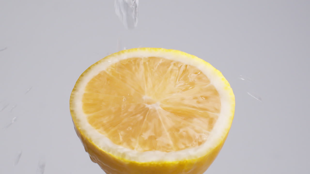 замедленная макросъемка стекающей воды с лимонной дольки на белом фоне