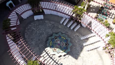 Aerial-top-down-view-of-a-reception-area-of-the-marriage,-wedding-ceremony-under-the-open-sky-with-white-folding-chairs