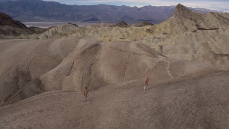two people explore vast arid desert mountains