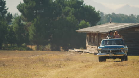 dos mujeres de pie en la parte trasera de la camioneta como amigos disfrutan de un viaje por carretera a la cabaña del campo