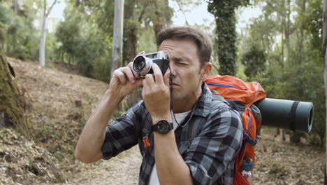 ragazzo zaino in spalla con la macchina fotografica per scattare foto della foresta