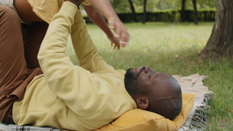 african american man lying in park and lifting excited little son