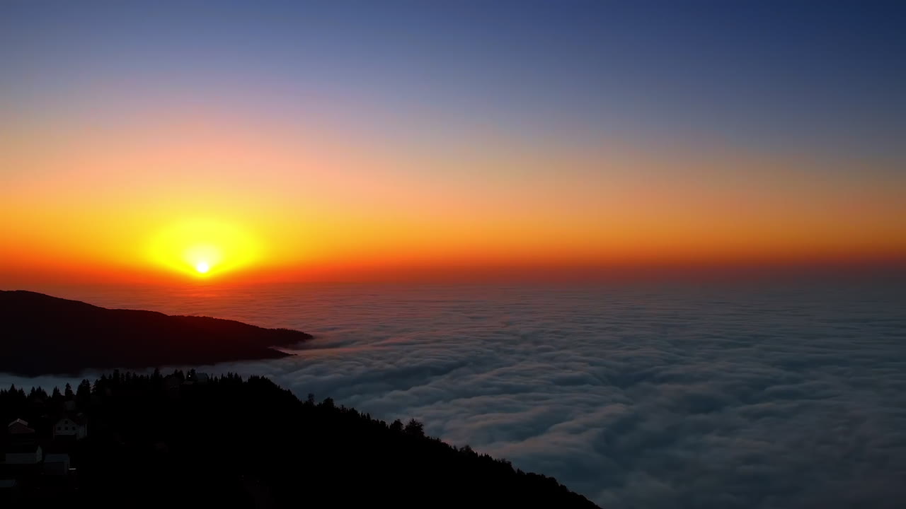 Sobrevoo da aldeia de montanha na floresta escura de pinheiros. O sol poente colore o céu acima de um denso manto de nuvens.