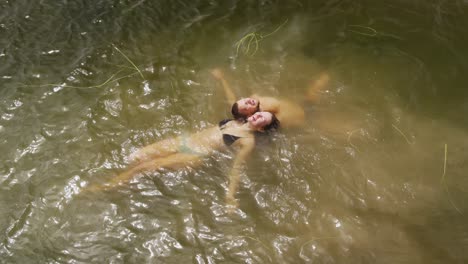 Caucasian-couple-having-a-good-time-on-a-trip-to-the-mountains,-wearing-bathing-suits-and-floating-o