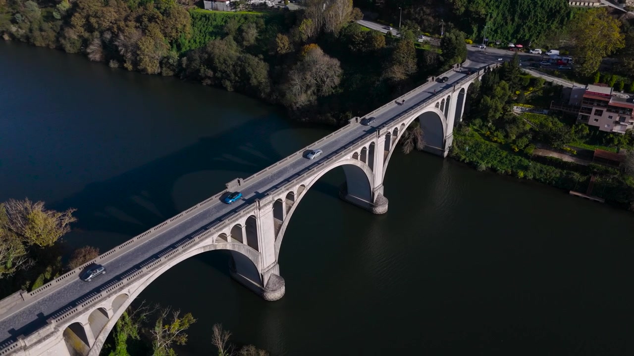 Vista circolare rotante da drone su un ponte di pietra con auto che passano in una giornata di sole, in Portogallo, Europa.