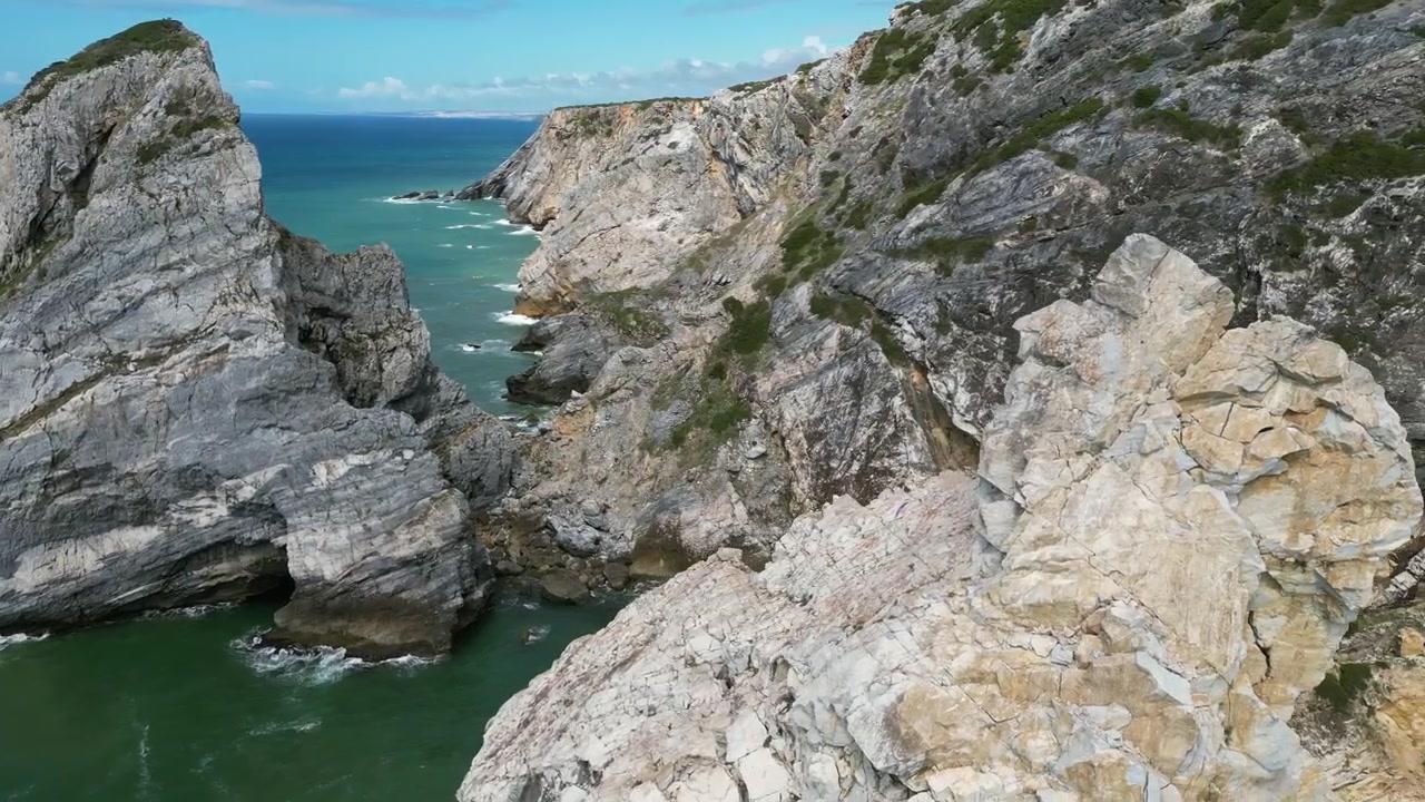 Aerial drone footage of Praia da Ursa, Portugal: dramatic sea stacks, Atlantic waves and rugged coastal scenery under natural light. Ideal for travel and nature projects.