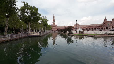 Pan-shot-of-tourists-boating-in-Plaza-de-Espana-along-Spanish-Square-in-Sevilla,-Spain-on-a-cloudy-evening