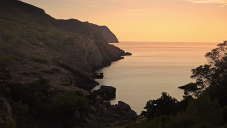 exploring rocky mountain cliffs, cove beach at golden hour sunset, dolly