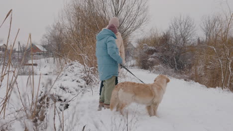 couple walking dog in snowy landscape