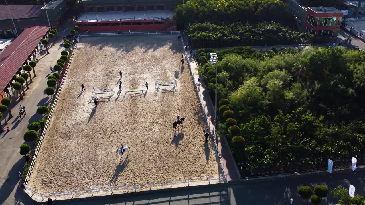 Equestres montando a cavalo e saltando em percurso de obstáculos em instalação equestre em Jeddah.