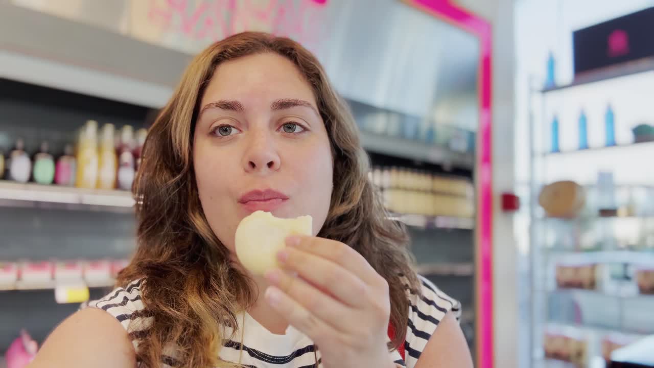 Woman Eating a Cookie in a Grocery Store