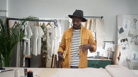 cheerful young designer drawing an outline on the cloth and dancing in studio 1