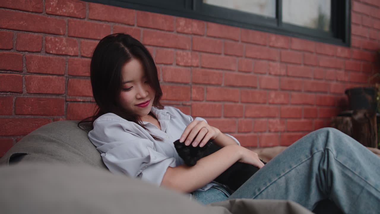 A woman cuddling a black cat indoors